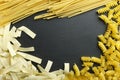 Different types of uncooked dried pasta on the black surface.Free space for text