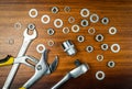 Different types of wrenches with nuts and washers on a brown wooden background