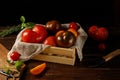 Different varieties of homemade tomatoes in a wooden box. Close-up, low key. Royalty Free Stock Photo