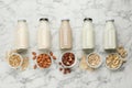 Different vegan milks and ingredients on white marble table, flat lay Royalty Free Stock Photo