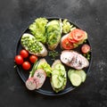 Different vegan sandwiches with vegetables, radish, tomato, rye bread on black. Appetizer for party. Royalty Free Stock Photo