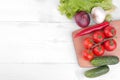 different vegetables including, tomatoes, peppers, cucumbers, onions, garlic and lettuce on a white wooden background. Top view Royalty Free Stock Photo