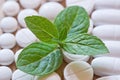 Different white pills and foliage mint on a wooden background Royalty Free Stock Photo