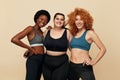 Different Women. Group Of Diversity Models Portrait. Smiling Multicultural Female In Fitness Clothes Posing On Beige Background.