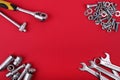 Different wrenches and heap of bolts and nuts on red background with copy space