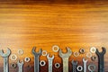 Different wrenches, nuts and washers on a brown wood texture background