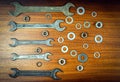 Different wrenches, nuts and washers on a brown wood texture background