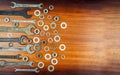 Different wrenches, nuts and washers on a brown wood texture background