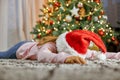 Difficult and difficult New Year and Christmas. Tired child. A cute little girl in a Santa hat lies face down on the Royalty Free Stock Photo