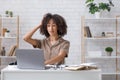 Difficult task or problems at online work. Surprised african american woman scratches her head and looks at laptop