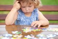 Difficult task. Tired child playing jigsaw with serious face. Royalty Free Stock Photo