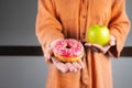 It is difficult to choose a healthy eating concept when a woman is holding a green apple and a donut with a lot of Royalty Free Stock Photo