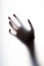 Diffused shadow of hand with thin fingers behind the frosted glass Royalty Free Stock Photo