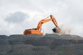 Digger collecting stone for road building