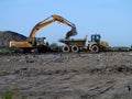 Digger and dumper truck working on waste ground reclamation