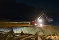 Digger excavator working at night time moving the ground at the beach for maintenance Royalty Free Stock Photo