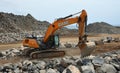 Digger moving large boulders on construction site.