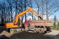 Digger moving soil. Excavator work on construction site at sunset. Earthmoving works. Yellow Backhoe digs sand Royalty Free Stock Photo