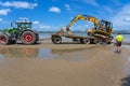 Digger on trailer behind tractor on beach Royalty Free Stock Photo