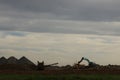 Diggers and trucks working together on a large industrial work site moving large stones and rubble into a large crusher to make Royalty Free Stock Photo