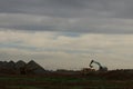 Diggers and trucks working together on a large industrial work site moving large stones and rubble into a large crusher to make Royalty Free Stock Photo