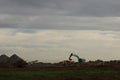 Diggers and trucks working together on a large industrial work site moving large stones and rubble into a large crusher to make Royalty Free Stock Photo