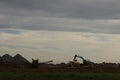 Diggers and trucks working together on a large industrial work site moving large stones and rubble into a large crusher to make Royalty Free Stock Photo