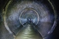 Diggers urban explorers are exploring underground river flowing in round sewer tunnel