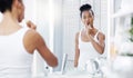 Digging deep to brush out all the cavities. an attractive young woman brushing her teeth while looking at the bathroom Royalty Free Stock Photo