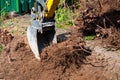 Digging out of trunk and roots with mini excavator. Tree stump removal Royalty Free Stock Photo