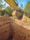 Digging the pit foundation a hole with excavator at the construction site. Excavator digging a hole into the ground Royalty Free Stock Photo