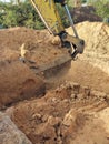 Digging the pit foundation a hole with excavator at the construction site. Excavator digging a hole into the ground Royalty Free Stock Photo