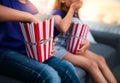 Digging right in. two unrecognizable young children sitting on a sofa and eating popcorn while watching movies at home. Royalty Free Stock Photo