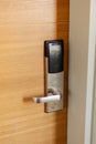 A digital access control system is installed on a wooden door. The device features a card reader and a handle. It is part of a Royalty Free Stock Photo