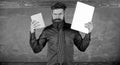 Digital against paper. Teacher bearded hipster holds book and laptop. What would you prefer. Teacher choosing modern