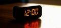 A digital alarm clock on a table or nightstand with the time at noon or midnight. Design element or background with copy space Royalty Free Stock Photo