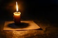 Digital artwork of  single candle burning in the darkness, casting its light on an empty paper letterhead. the simplicity of Royalty Free Stock Photo