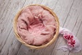 Newborn round wicker basket with pink fluffy wool and pink flowers