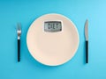 Digital bathroom scale screen with the word diet on a plate with fork and knife