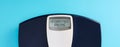 Digital bathroom scale with the word intermittent fasting on blue background