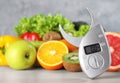 Digital body fat caliper, vegetables and fruits on table. Diet plan from nutritionist