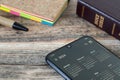 Digital calendar 2024 on smartphone screen with closed holy bible book and notebook on wooden table