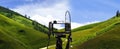 Digital camera on camera tripod taking a photo of panoramic green hills landscape, selective focus on camera