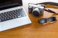 Digital camera, laptop computer, and sunglasses on wooden table Royalty Free Stock Photo