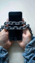 Digital captivity Mobile phone chained to hands, symbolizing social media addiction