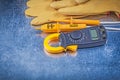 Digital clamp meter electrical tester safety gloves on metallic Royalty Free Stock Photo