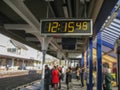 Digital clock marking 12:15:49, at a London train station