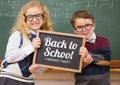 back to school text on blackboard with two school kids