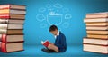 Boy reading surrounded by pile of books and a drawing with blue background Royalty Free Stock Photo