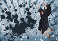 Excited young student man jumping and holding a diploma against blue splattered background